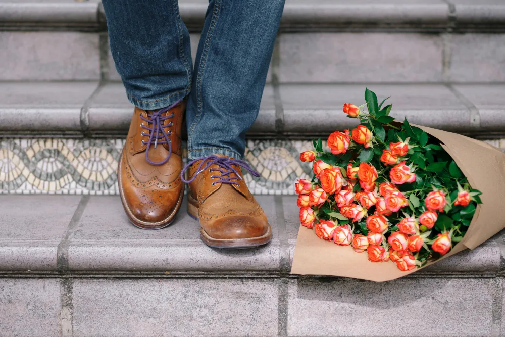 Ein Paar Budapester Schuhe neben einem Blumenstrauß