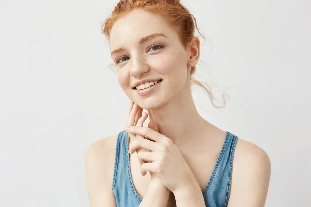 Junge Frau mit hellem Teint und Sommersprossen in einem blauen Sommeroberteil