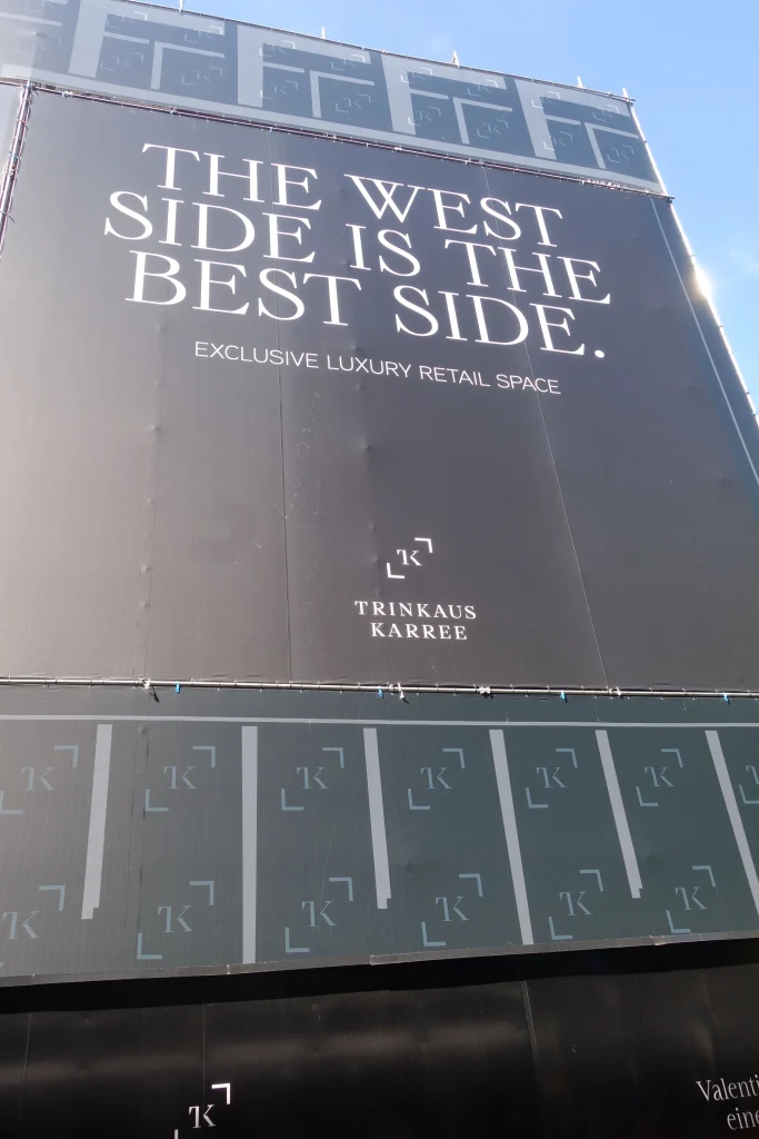 Bauzaun am Trinkaus Karree auf der Westseite der Königsallee in Düsseldorf mit dem Schriftzug „The west side is the best side“.