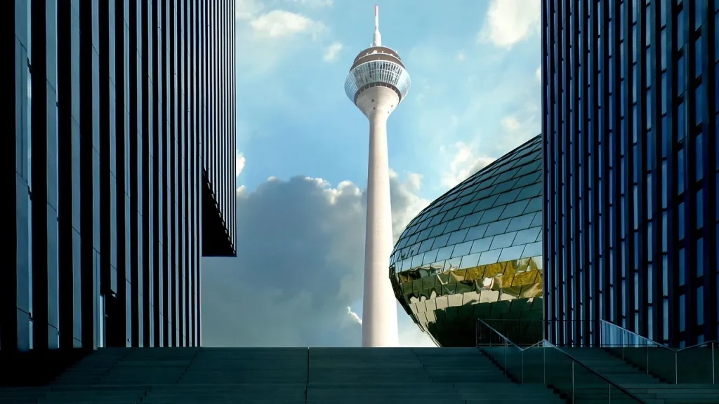 Rheinturm im MedienHafen Düsseldorf, eingerahmt von moderner Büroarchitektur und Treppenanlage.