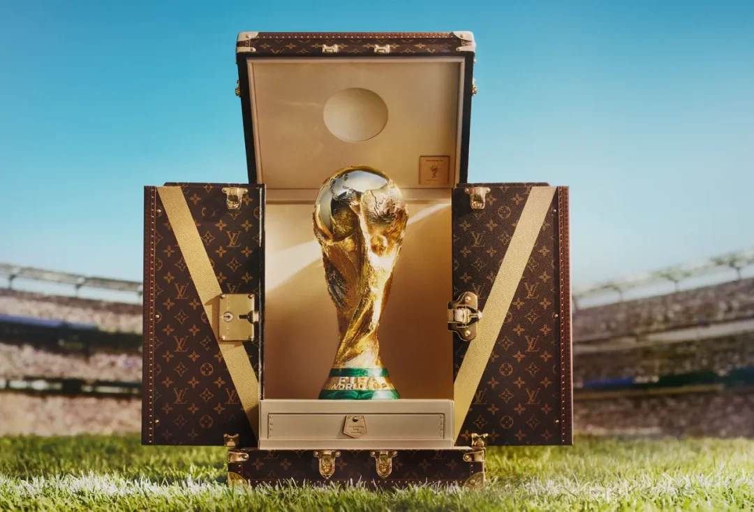 Der WM-Pokal 2026 steht in einem geöffneten Louis-Vuitton-Trophäenkoffer auf dem Rasen eines Fußballstadions.