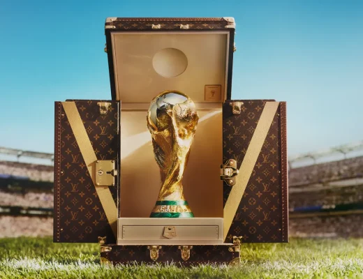 Der WM-Pokal 2026 steht in einem geöffneten Louis-Vuitton-Trophäenkoffer auf dem Rasen eines Fußballstadions.