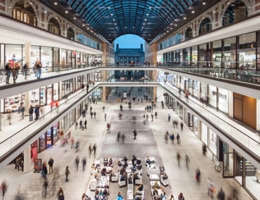 Innenansicht der Mall of Berlin mit Glasdach, Geschäften und Besuchern.