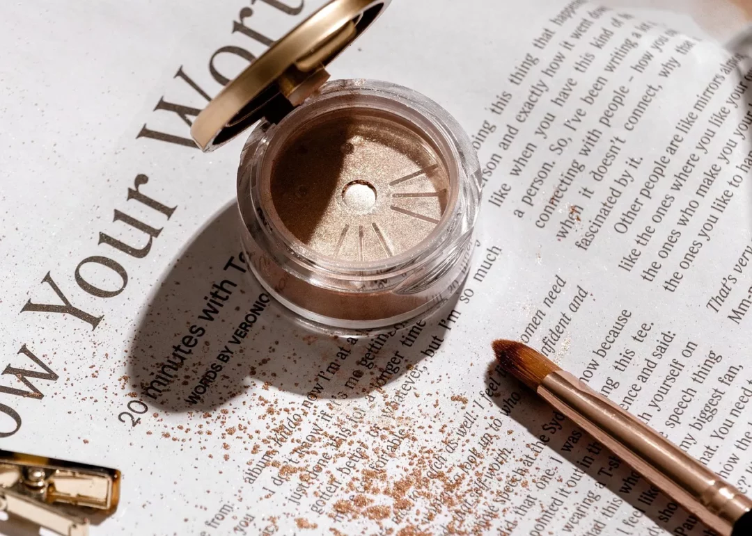 Goldener Lidschatten im Tiegel mit Pinsel – Symbol für Drogerie vs. Luxus Make-up Vergleich