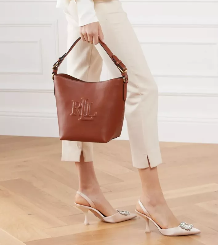 Braune Bucket Bag aus Leder von Ralph Lauren, kombiniert mit cremefarbener Hose und eleganten Slingback-Pumps.