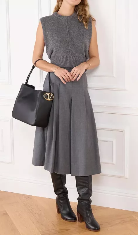 Schwarze Bucket Bag von Valentino, kombiniert mit grauem Stricktop, Midirock und schwarzen Lederstiefeln.