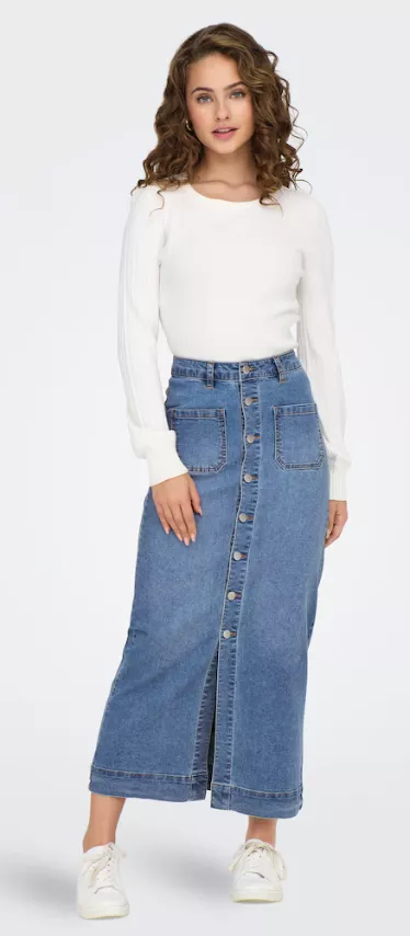 Frau trägt Maxi-Jeansrock Outfit 2025 – blauer Denimrock mit Knopfleiste, kombiniert mit weißem Pullover und weißen Sneakers.