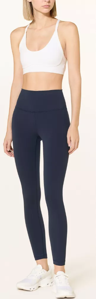 Frau trägt Lululemon Leggings in Dunkelblau und weißen Sports Bra – minimalistisches Athleisure-Outfit mit Sneakern