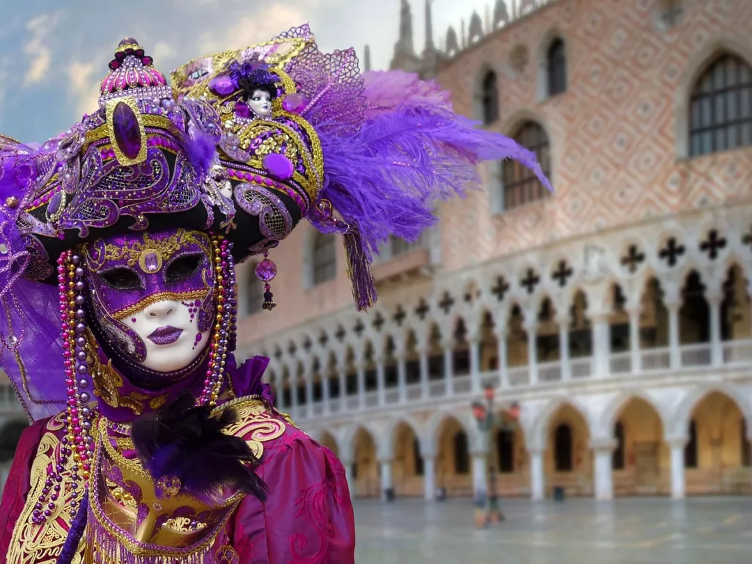 Maskierte Gestalt in violett-goldenen Kostümen vor dem Dogenpalast – künstlerisches Symbol für die Filmfestspiele Venedig 2025.