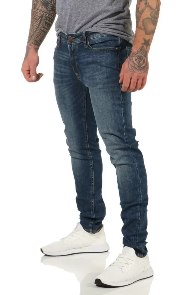 Mann trägt blaue Skinny Jeans Herren mit grauem T-Shirt und weißen Sneakers – moderner Denim-Trend 2025