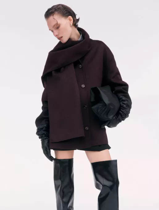 Mantel Damen bordeaux – kurzer Wollmantel mit Oversize-Schal, schwarze Lederhandschuhe und Overknee-Stiefel zu Minirock/Shorts vor hellem Hintergrund.