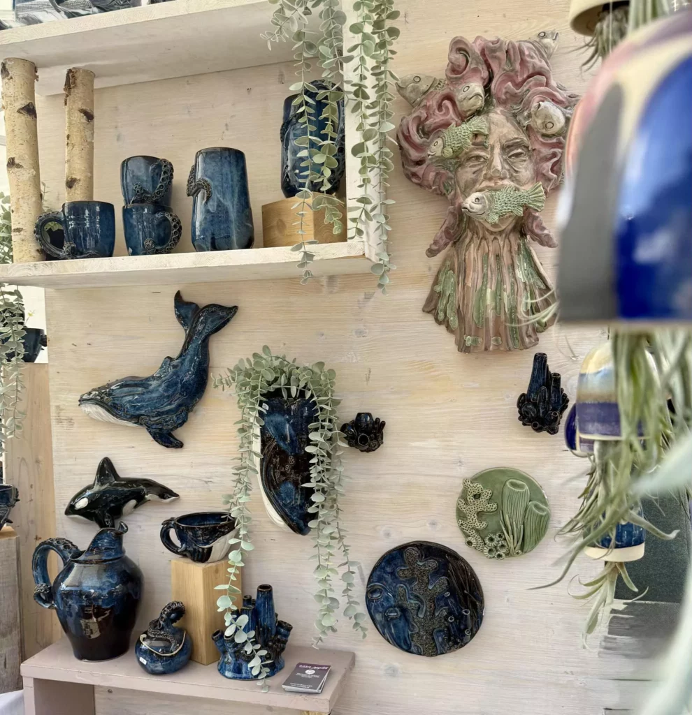 Keramikobjekte mit maritimen Motiven wie Walen, Delfinen und abstrakten Figuren, glasiert in tiefem Blau, ausgestellt auf dem Töpfermarkt Neu-Ulm 2025.