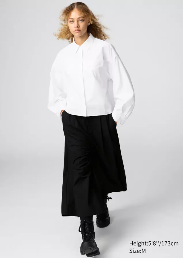 Model trägt Uniqlo Outfit mit weißem Oversize-Hemd, weiter schwarzer Hose und schwarzen Boots im minimalistischen Stil
