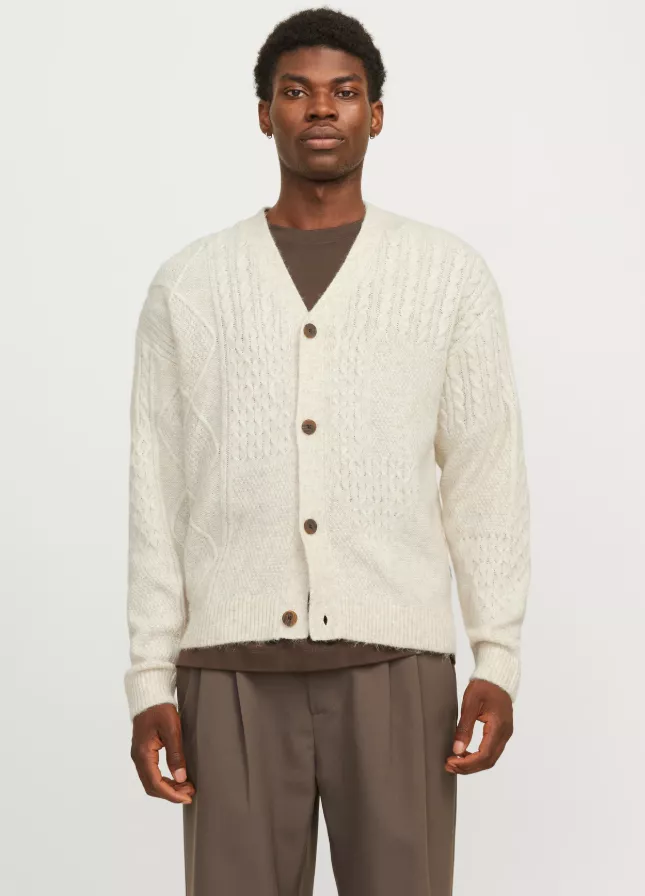 Cardigan vs. Strickjacke – Mann trägt beigen Herren-Cardigan mit Knopfleiste über braunem Shirt und Stoffhose