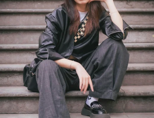Junge Frau im modernen Korean-Style mit schwarzem Hut und Oversized-Look auf einer Treppe