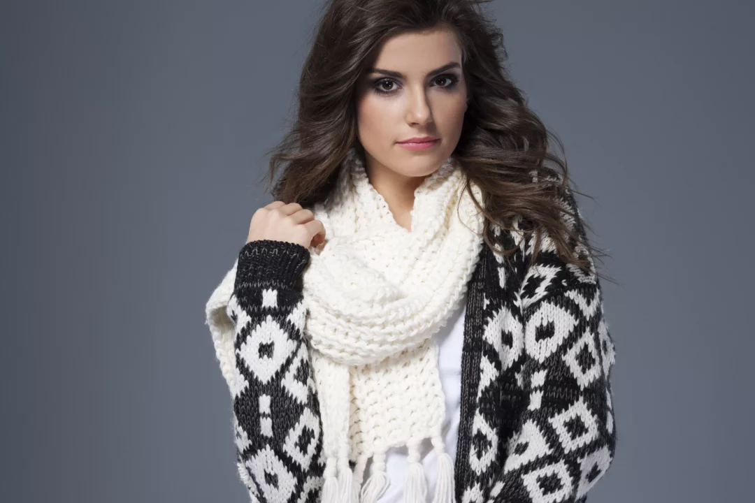 Cardigan vs. Strickjacke – Frau trägt gemusterte Strickjacke im Cardigan-Stil mit weißem Strickschal, moderner Winterlook 2025