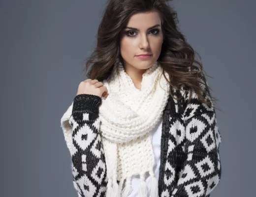 Cardigan vs. Strickjacke – Frau trägt gemusterte Strickjacke im Cardigan-Stil mit weißem Strickschal, moderner Winterlook 2025