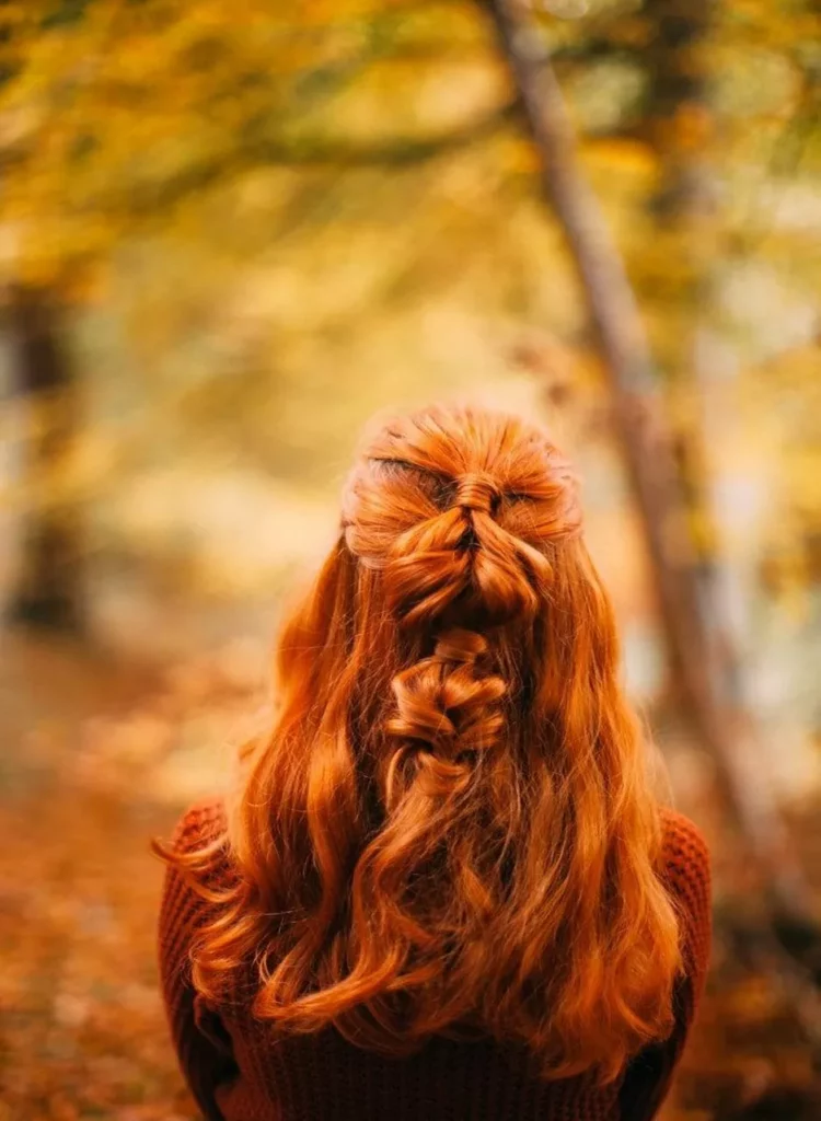Rote haare mit geflochtener Frisur im Herbstwald, leuchtendes Kupfer in natürlichem Licht.
