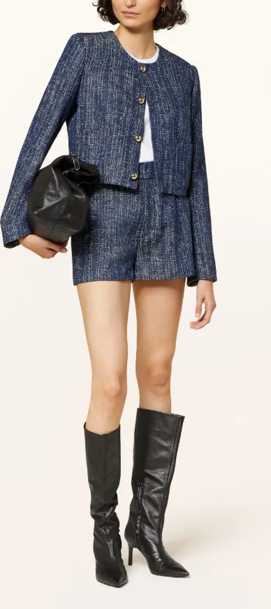 Blaue Tweed-Jacke mit goldenen Knöpfen, kombiniert mit passenden Shorts, weißen Shirt, kniehohen Stiefeln und Clutch – eleganter Herbstlook.