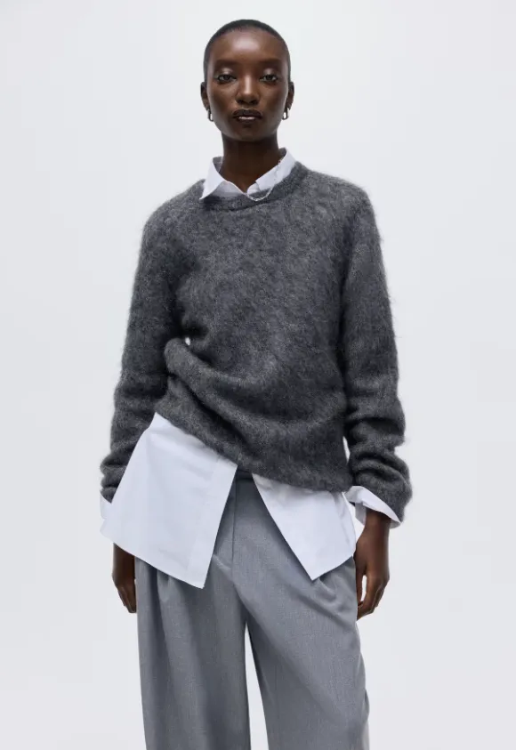 Grauer flauschiger Pullover über weißem Hemd, kombiniert mit grauer Bundfaltenhose – cleaner Herbst-Streetstyle-Look in Grau.