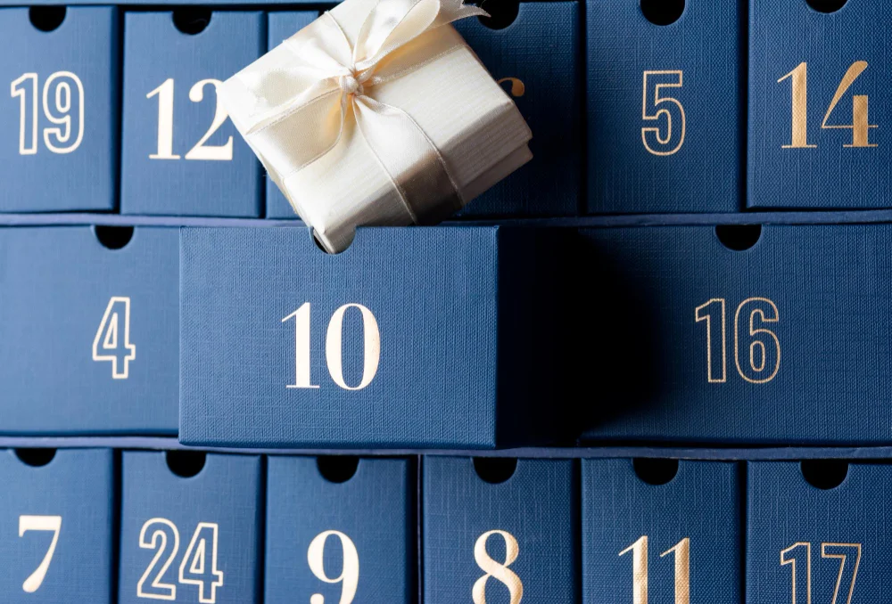 Blauer Adventskalender mit goldenen Zahlen und kleinem Geschenk – Adventskalender für Männer 2026