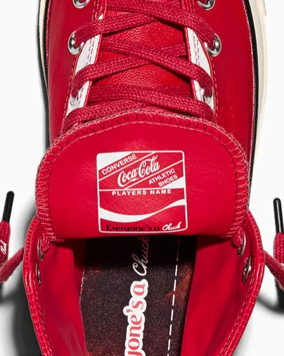 Nahaufnahme der Zunge und Schnürung des Converse x Coca-Cola Chuck 70 Leather in Racing Red mit Co-Branding-Label und cremefarbener Zwischensohle.