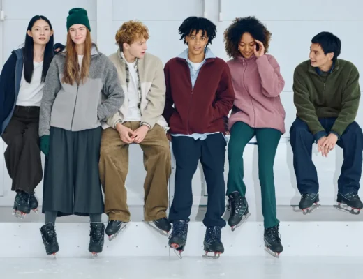 Uniqlo München – junge Menschen in Fleece- und Basics-Looks sitzen mit Eislaufschuhen auf einer Bank in heller Eishalle.