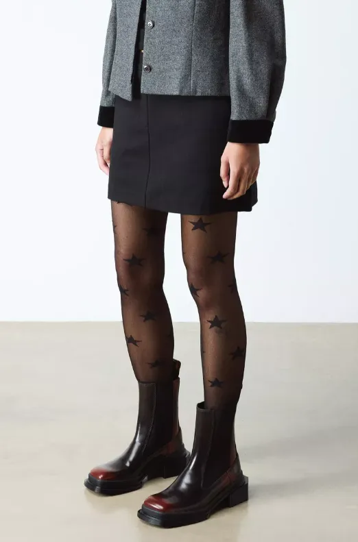 Damenlook mit zweifarbigen Chelsea Boots in Bordeaux-Schwarz, Minirock und transparenter Stern-Strumpfhose