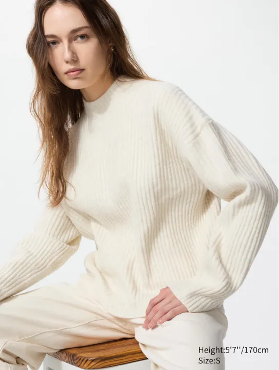 Uniqlo München – Damen trägt cremeweißen Soufflé-Yarn-Strickpullover mit Stehkragen, minimalistische Studioaufnahme.