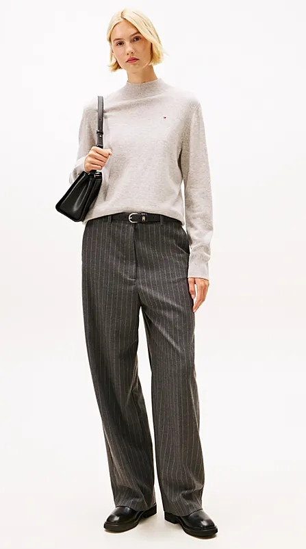 Hellgrauer Feinstrick-Pullover mit Stehkragen zu anthrazitfarbener Nadelstreifenhose, schwarzer Schultertasche und Loafern – minimalistischer Business-Casual-Look.