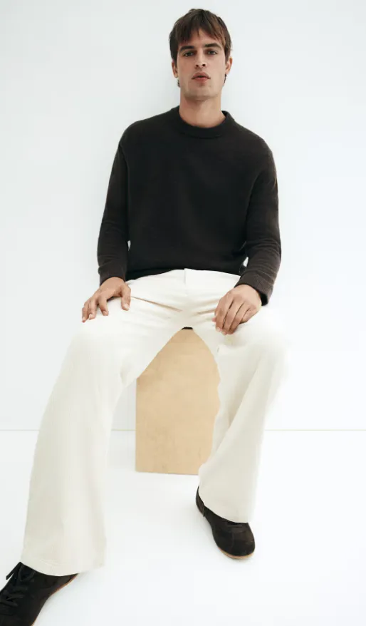 Cordhose Herren Trend 2025: cremefarbene Wide-Leg-Cordhose kombiniert mit dunkelbraunem Strickpullover und Wildleder-Loafern – minimalistischer Herbstlook