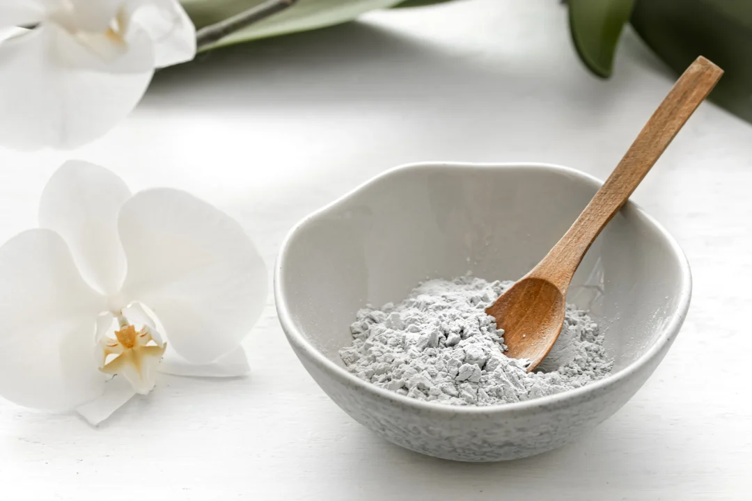 Kollagen Pulver in einer grauen Keramikschale mit Holzlöffel neben einer weißen Orchideenblüte – minimalistisches Beauty-Stillleben für Hautpflege und Anti-Aging.