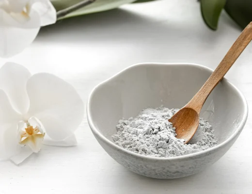 Kollagen Pulver in einer grauen Keramikschale mit Holzlöffel neben einer weißen Orchideenblüte – minimalistisches Beauty-Stillleben für Hautpflege und Anti-Aging.
