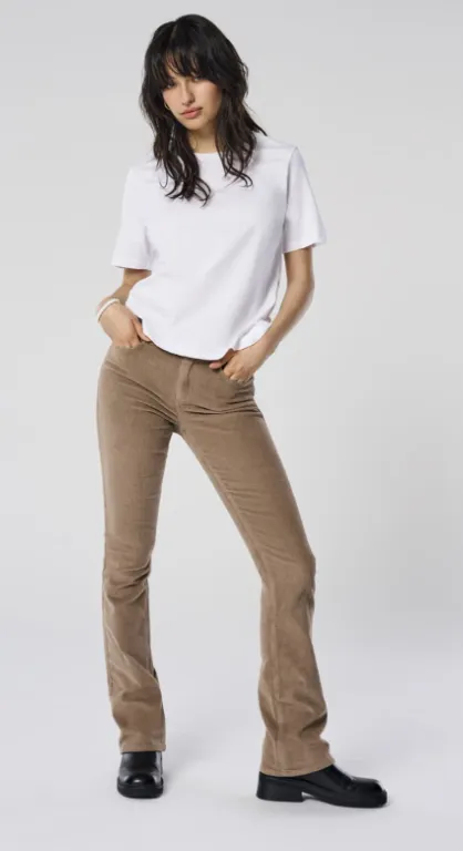 Cordhose Damen Herbstrend: schlanke Flared-Cordhose in Karamellbraun, weißes T-Shirt, schwarze Loafer – cleaner Herbstlook im Studio