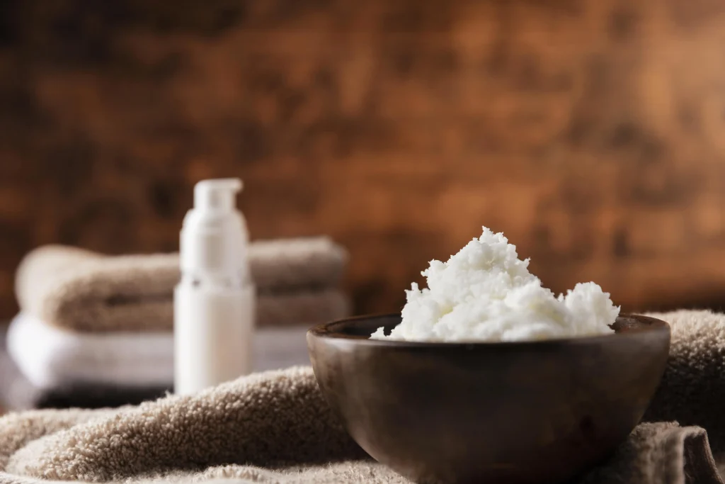 Whipped tallow-Balm in dunkler Holzschale, davor Frotteehandtücher und Lotionpumpe – Spa-Setting für Naturkosmetik und Hautpflege