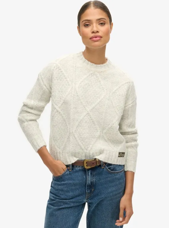 Heller, cremefarbener Struktur-Pullover mit Rautenstrick und Rundhalsausschnitt, kombiniert mit Mid-Blue-Jeans und braunem Ledergürtel – cleaner Casual-Look.