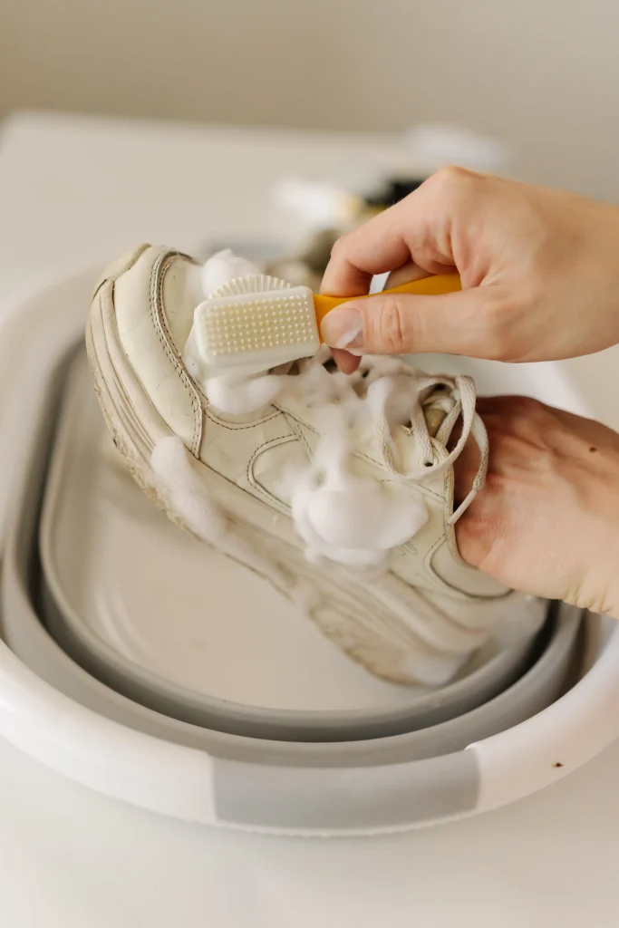 Sneaker waschen: weiße Sneaker werden mit einer kleinen Bürste und Reinigungsschaum per Hand gereinigt