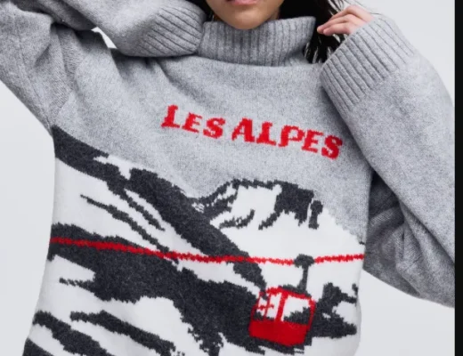 Damen-Weihnachtspullover in Grau mit alpinem Motiv, roter Seilbahn und „Les Alpes“-Schriftzug, getragen in einem modernen Winterlook.