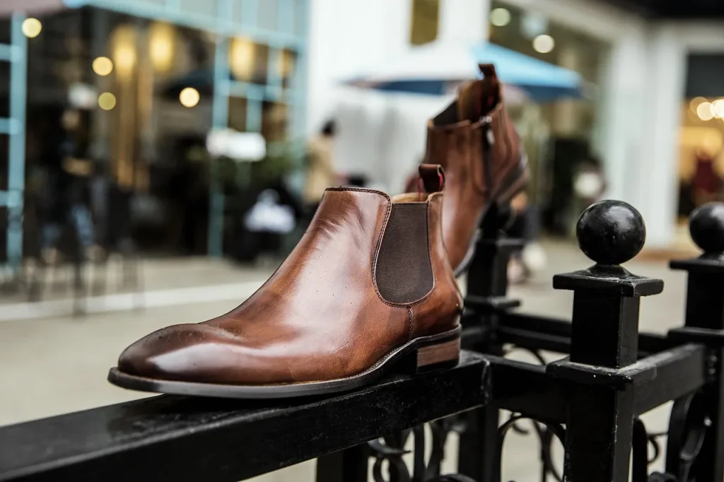 Klassische braune Chelsea Boots aus Glattleder, detailreich fotografiert im urbanen Umfeld.