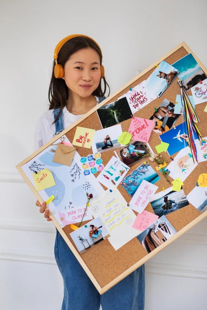 Frau hält ein selbst erstelltes Vision Board mit Bildern, Zitaten und persönlichen Zielen