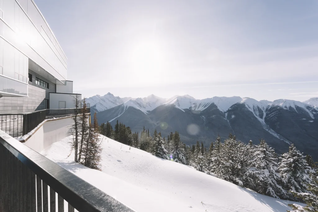 Alpenpanorama mit modernem Chalet-Gebäude und Blick auf schneebedeckte Berge in Italien.