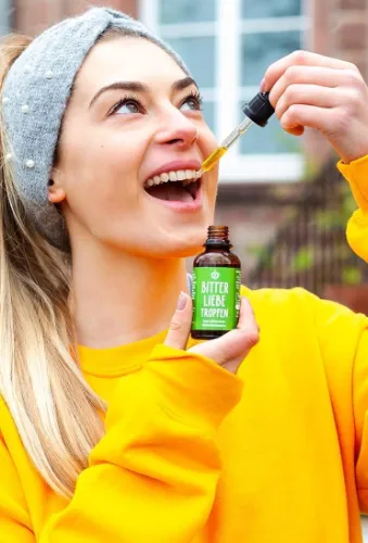 Frau nimmt BitterLiebe Bittertropfen mit Pipette aus einer Glasflasche ein