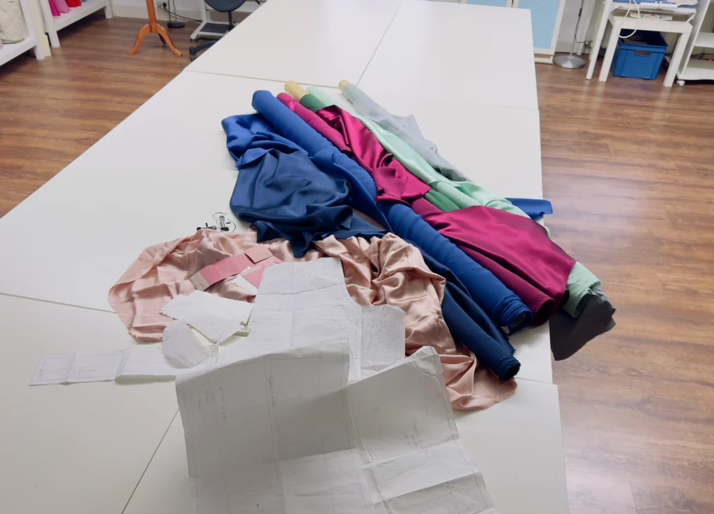 Seide im Atelier: Stoffbahnen und Schnittmuster auf dem Arbeitstisch