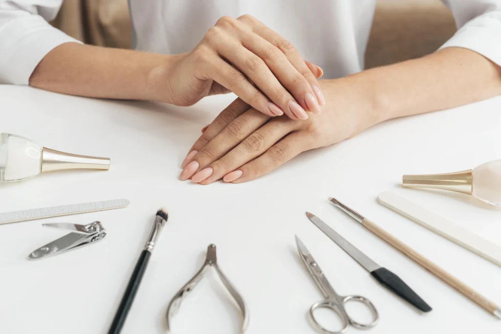 Manik&uuml;re-Werkzeuge und gepflegte Fingern&auml;gel auf hellem Tisch als Symbol f&uuml;r eine strukturierte Nagelpflege-Routine.