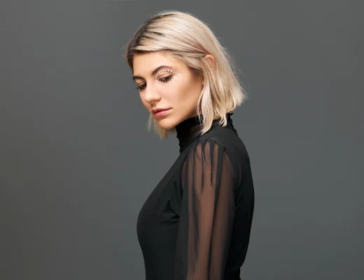 Blonde Person mit kinnlangem Blunt Bob und Seitenscheitel, moderner Bob-Schnitt mit klarer Linie vor neutralem Hintergrund