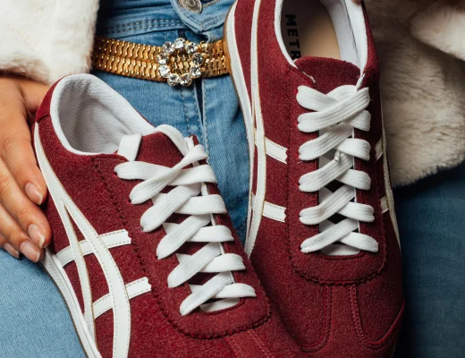 Sportlicher Damen-Sneaker in Bordeauxrot mit weißer Schnürung, kombiniert mit Jeans und modischen Accessoires