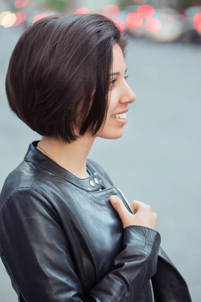 Seitliche Ansicht eines kinnlangen Blunt Bob mit klarer Schnittlinie, moderner Bob-Schnitt bei dunklem Haar im urbanen Umfeld