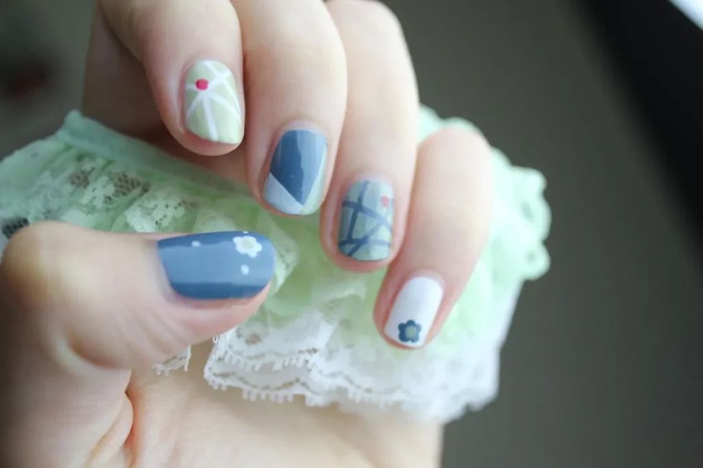 Frühlingsnägel 2026 mit grafischer Nail Art in Blau und Grün, kurze Nägel mit floralen und geometrischen Mustern