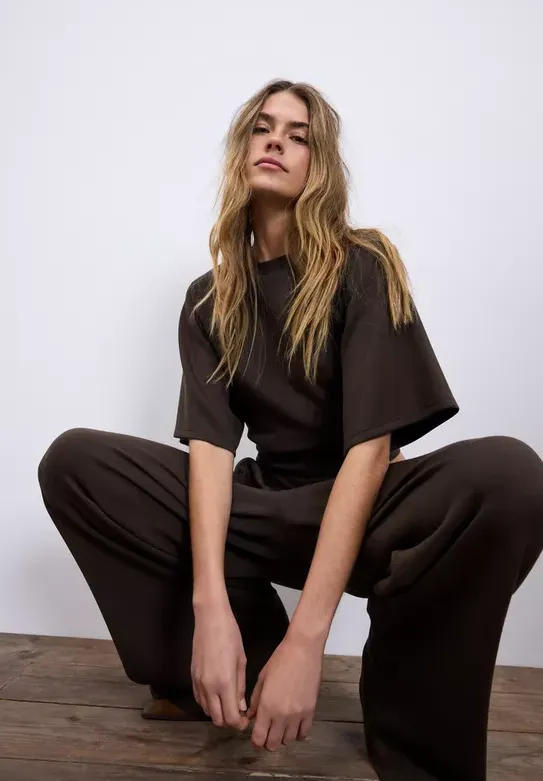 Model tr&auml;gt braunes Outfit mit T-Shirt und Hose &ndash; moderner Look in der Trendfarbe Braun 2026