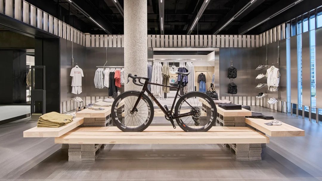 Ein stylisches Fahrrad auf einem Holztisch inmitten eines modernen Geschäftslokals mit Herrenbekleidung